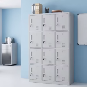 Premium 15 Locker Office Steel Cabinet in a professional light grey powder-coated steel finish, showcasing a 3x5 grid layout of fifteen closed locker doors with recessed handles, cylinder locks with keys inserted, name card frames, and stamped bottom ventilation patterns, standing flat on smooth light wood flooring against a textured grey wall.