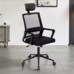 Mesh Ergonomic Office Seat in black color featuring a high-back breathable mesh design, an adjustable headrest, fixed armrests, and a 5-star rolling caster base next to a white office desk.
