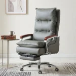 Premium slate grey Executive Reclining Office Chair featuring double-layered plush pillow-top cushions, polished mahogany wood armrest accents, a retractable under-seat footrest, and a mirror-polished chrome steel wheelbase.