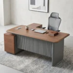 Premium L-shaped Modern Executive Office Table featuring a natural walnut grain desktop with rounded edges, a grey fluted vertical modesty panel, and a matching integrated side-return credenza cabinet.
