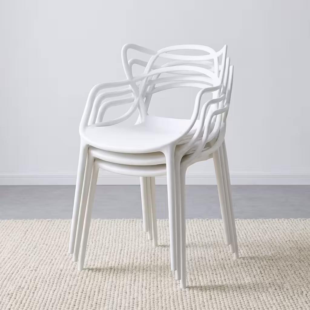 White Bistro Plastic Chair with an intricate, sweeping cut-out backrest and integrated arms, placed on a modern concrete backyard patio.