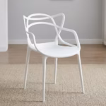 White Bistro Plastic Chair with an intricate, sweeping cut-out backrest and integrated arms, placed on a modern concrete backyard patio.