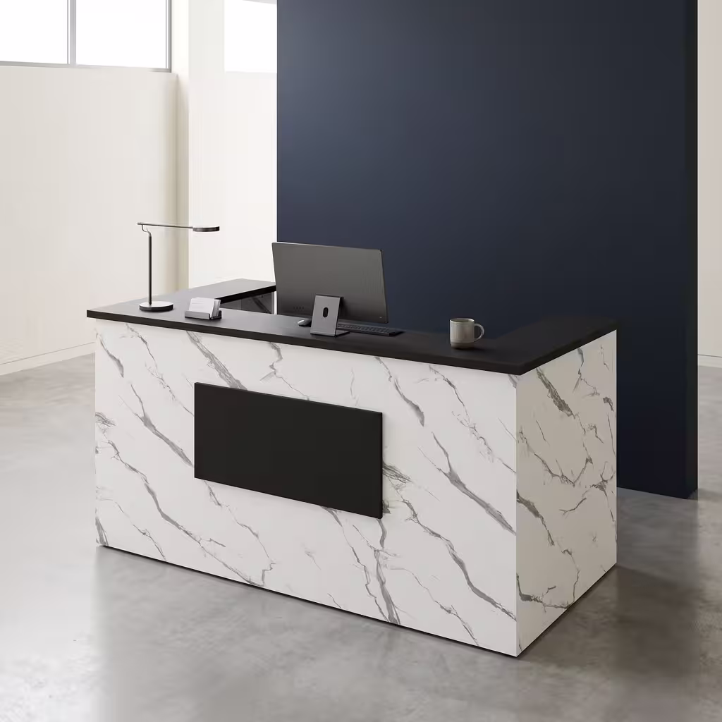 Premium 1.6M Office Front Reception Desk featuring a white marble-patterned panel facade with a center-set black rectangular accent plaque, a thick matte black privacy transaction top supporting a desktop monitor, desk lamp, and a grey ceramic mug, resting on a polished concrete floor against a dark navy wall.