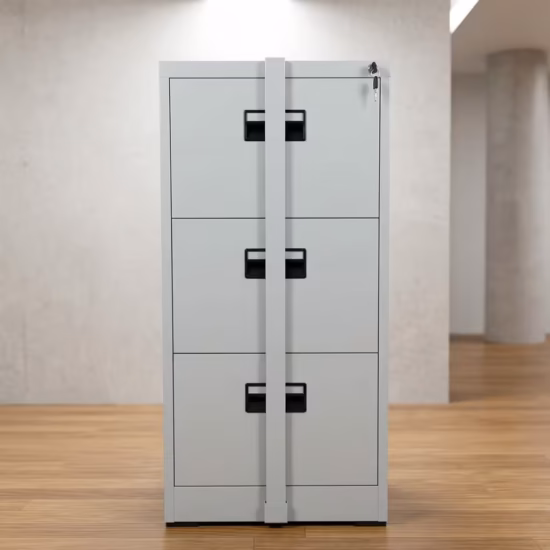 Premium 3-Drawer Locking File Cabinet in a professional light gray powder-coated steel finish, showing all three closed drawers secured by a centered vertical steel locking bar with a key inserted in the top lock core, standing on light wood flooring in a modern office setup.