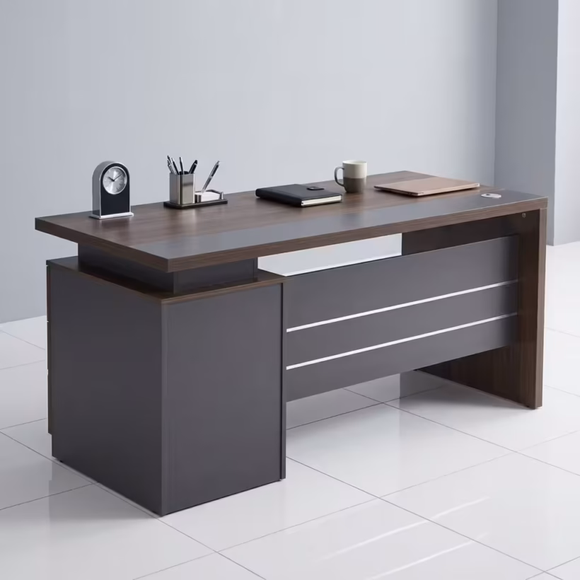 Premium 1.2M Executive Modern Wooden Office Desk in a dark walnut woodgrain finish, featuring a matte charcoal grey front modesty panel with three horizontal silver accent lines, an integrated left-side storage pedestal cabinet, a desktop supporting a modern clock, pen organizer, notebook, mug, and laptop on a polished white tile floor.