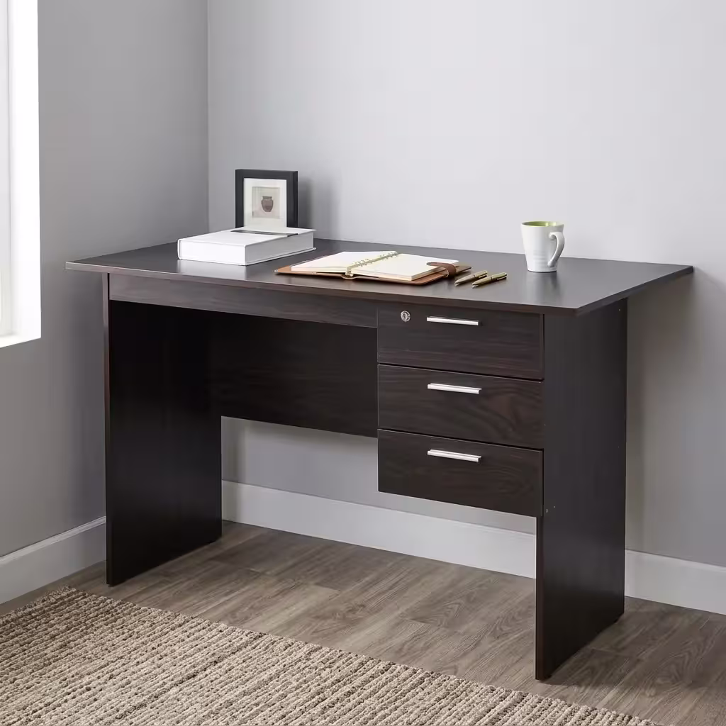 Premium 1.2M Wooden Custom Office/Home Desk in a dark espresso woodgrain finish, showcasing a flat rectangular tabletop supporting an open notebook and book, an integrated 3-drawer storage pedestal with a top key lock and silver bar handles, standing on wood-paneled flooring next to a textured beige rug