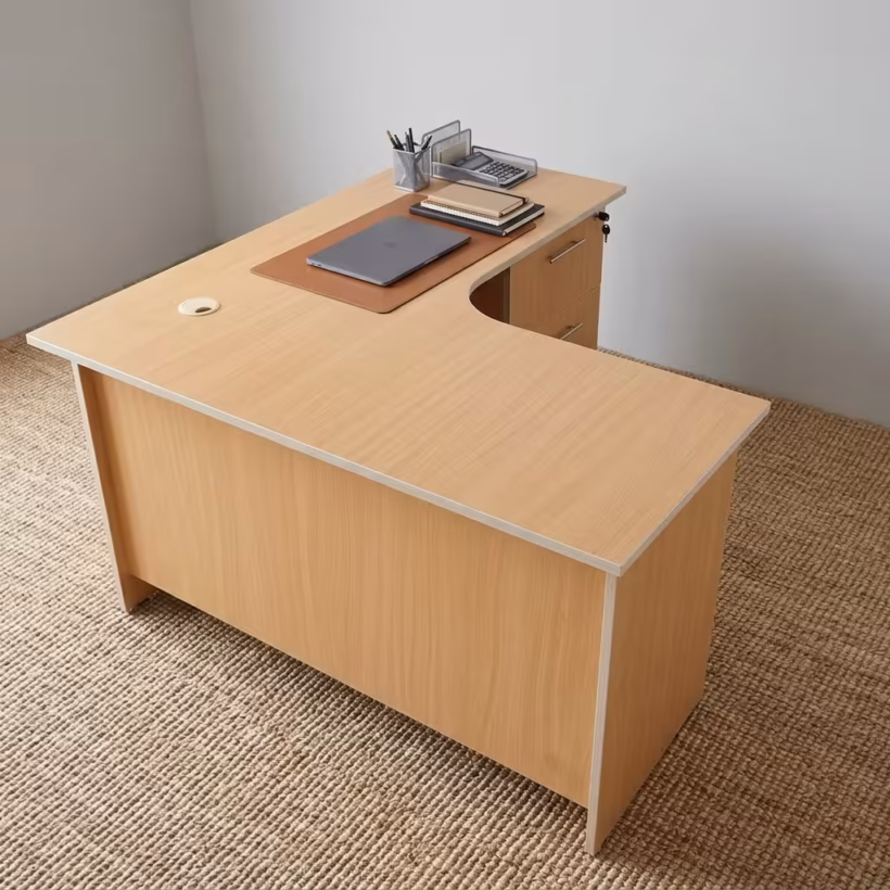 Premium 1.4M Curved Desk With Drawers in a warm beech woodgrain finish, showcasing a flat rectangular right-hand curved tabletop supporting a silver laptop on a leather mat, notebooks, and a wire pencil holder, with an integrated storage drawer pedestal with a key lock, resting on a textured light tan area rug.