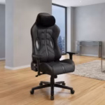 Premium High-Back Ergonomic Black Modern Gaming Chair in a sleek matte black faux leather upholstery, featuring a contoured bucket backrest, an adjustable neck headrest pillow, a matching lower lumbar cushion, rigid armrests, and a heavy-duty black five-star star base with rolling wheels, standing on a polished floor.