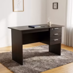 Premium 1.2M Wooden Custom Office/Home Desk in a dark espresso woodgrain finish, showcasing a flat rectangular tabletop supporting an open notebook and book, an integrated 3-drawer storage pedestal with a top key lock and silver bar handles, standing on wood-paneled flooring next to a textured beige rug