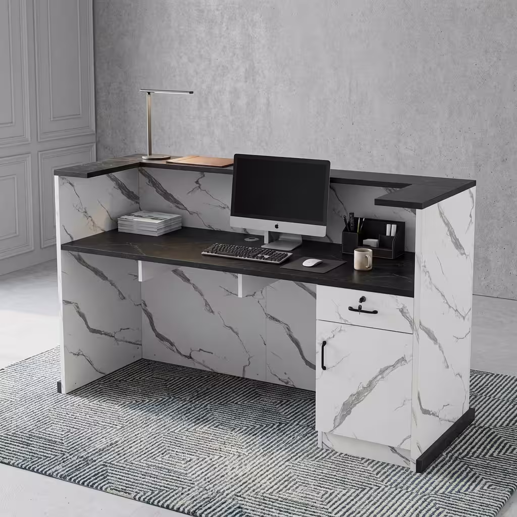 Premium 1.6M Office Front Reception Desk featuring a white marble-patterned panel facade with a center-set black rectangular accent plaque, a thick matte black privacy transaction top supporting a desktop monitor, desk lamp, and a grey ceramic mug, resting on a polished concrete floor against a dark navy wall.