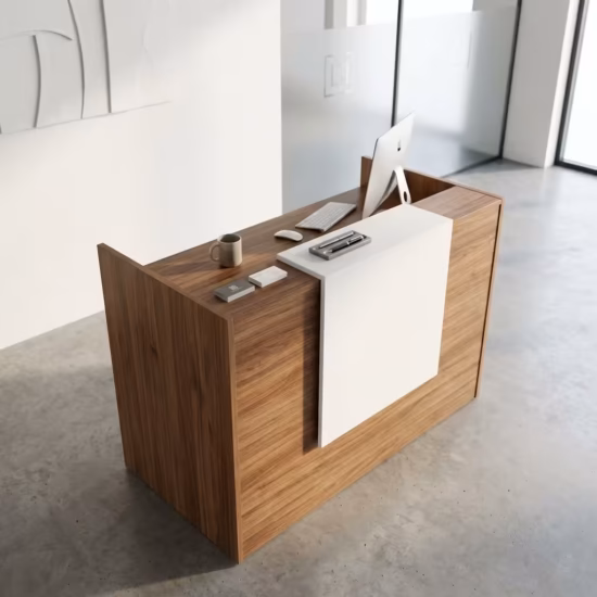 Premium 1.2M Wooden Reception Counter Office Desk featuring a rich walnut woodgrain panel facade, a center-set cascading waterfall-edge white transaction counter supporting a silver laptop, a pen holder set, and stacked books, resting on a polished grey concrete floor.