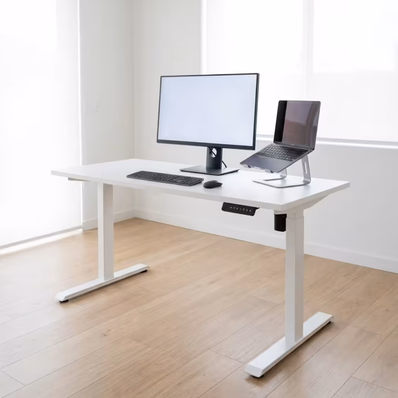 Premium 1.4M Height Adjustable Electric Desk in a minimalist white finish, showing a dual-monitor setup raised to a standing height position in a bright home studio.
