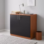 Premium 2-Door Wooden Storage Office Cabinet in a rich walnut woodgrain finish, showcasing two closed vertical swing doors with a centered silver key lock cylinder, standing on a polished concrete floor in a modern corporate office layout.