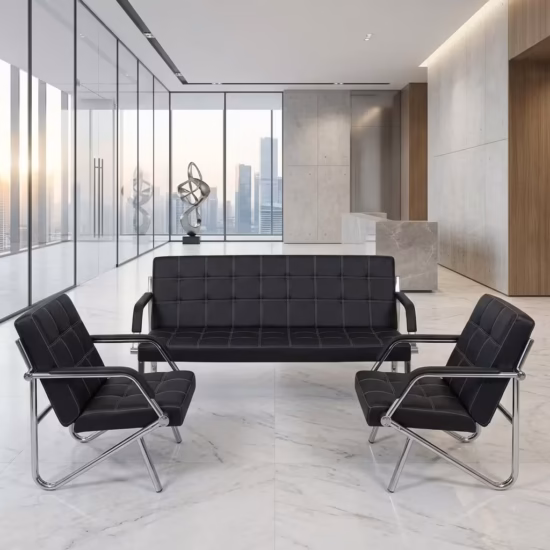 Premium 3+1+1 Executive Office Sofa Set in black faux leather with square box stitching and reflective continuous chrome steel tube frames, arranged as a 3-seater couch and two facing armchairs on a white marble floor in a corporate lobby.