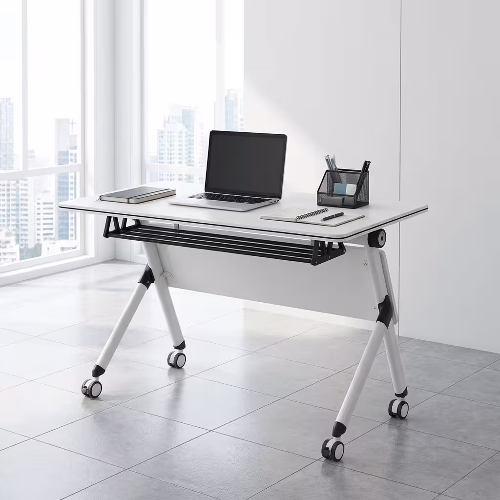 Premium 1.2M Foldable Training Office Table with a smooth white top, front black privacy baffle, and a white metal frame on lockable caster wheels, shown in a modern classroom.
