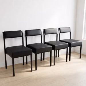 Premium Leather Padded Office Visitor Chair featuring matte black faux leather cushions and a sturdy black powder-coated metal frame, standing on a light wood floor.