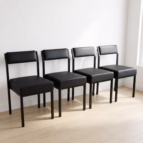 Premium Leather Padded Office Visitor Chair featuring matte black faux leather cushions and a sturdy black powder-coated metal frame, standing on a light wood floor.
