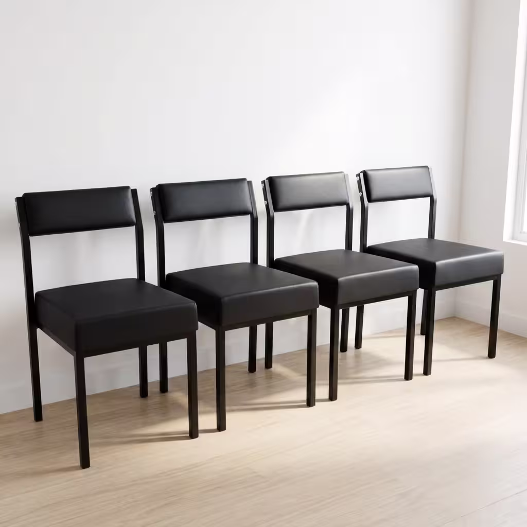 Premium Leather Padded Office Visitor Chair featuring matte black faux leather cushions and a sturdy black powder-coated metal frame, standing on a light wood floor.