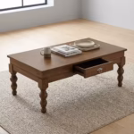 Premium Wooden Coffee Table With Storage in a rich mahogany finish, showcasing a central drawer with a metallic ring pull, a slatted bottom shelf, and carved turned legs on a plush area rug.