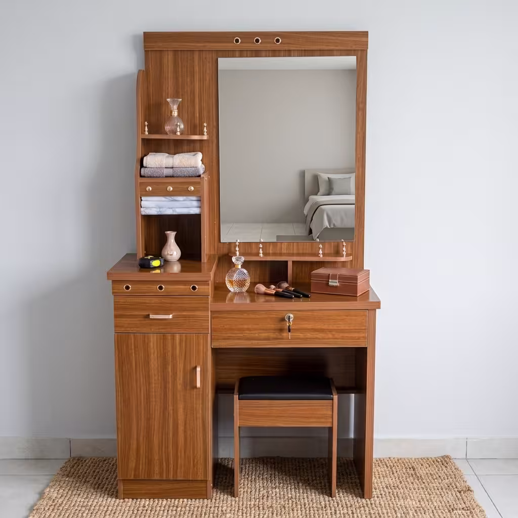 Premium Wooden Dressing Table With Storage in a rich natural oak finish, featuring an integrated center vanity mirror, multi-tier side display shelves with towels, a lockable main drawer, a lower cabinet door, and a matching slide-in cushioned vanity stool on a woven area rug.