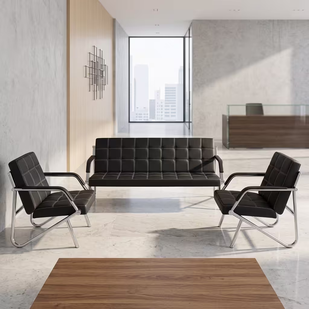 Premium 3+1+1 Executive Office Sofa Set in black faux leather with square box stitching and reflective continuous chrome steel tube frames, arranged as a 3-seater couch and two facing armchairs on a white marble floor in a corporate lobby.