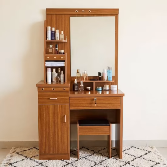 Premium Wooden Dressing Table With Storage in a rich natural oak finish, featuring an integrated center vanity mirror, multi-tier side display shelves with towels, a lockable main drawer, a lower cabinet door, and a matching slide-in cushioned vanity stool on a woven area rug.