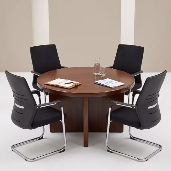 Premium 4-Seater Round Wooden Conference Table featuring a smooth circular tabletop with a rich mahogany woodgrain finish, supported by a heavy-duty intersecting cross-panel pedestal base, surrounded by four black mesh cantilever chairs in a corporate studio setup.