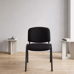 Premium Tosca Stackable Visitor Chair featuring rounded black fabric cushions, an armless low-back profile, and a sturdy four-legged matte black steel frame, standing on a light wood floor against a grey wall.