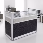 Premium One-Way Modular Office Workstation in a rich walnut woodgrain finish, showcasing a single rectangular tabletop with an integrated privacy partition panel, a lockable storage drawer unit with a key inserted, displaying a silver laptop and a ceramic mug, standing on a polished concrete floor.