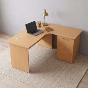 Premium 1.4M Curved Desk With Drawers in a warm beech woodgrain finish, showcasing a flat rectangular right-hand curved tabletop supporting a silver laptop on a leather mat, notebooks, and a wire pencil holder, with an integrated storage drawer pedestal with a key lock, resting on a textured light tan area rug.