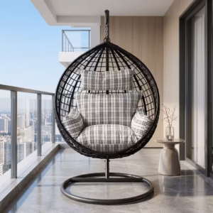 Premium 1-Seater Modern Rattan Hammock Swing featuring a black hand-woven teardrop wicker basket, a heavy-duty dark gray steel hanging stand, and plush black-and-white plaid cushions, placed on a high-rise balcony overlooking a city skyline.