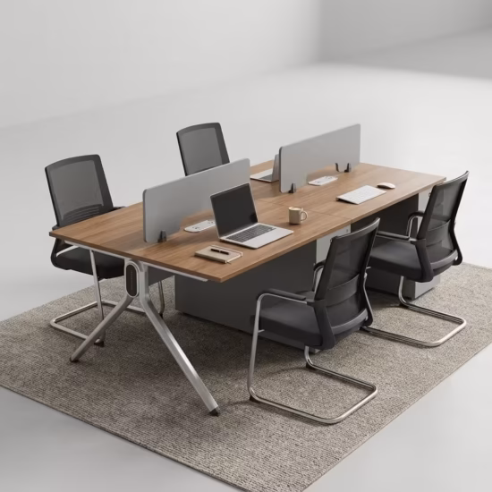 Premium 4-Way Modern Staff Office Workstation featuring a 4-person back-to-back island layout with walnut woodgrain desktops, integrated matte grey privacy partition screens, a heavy-duty angled aluminum A-frame base, and a central box wire enclosure, paired with four black mesh visitor chairs with chrome cantilever sled bases, resting on a textured beige area rug inside a modern minimalist office.