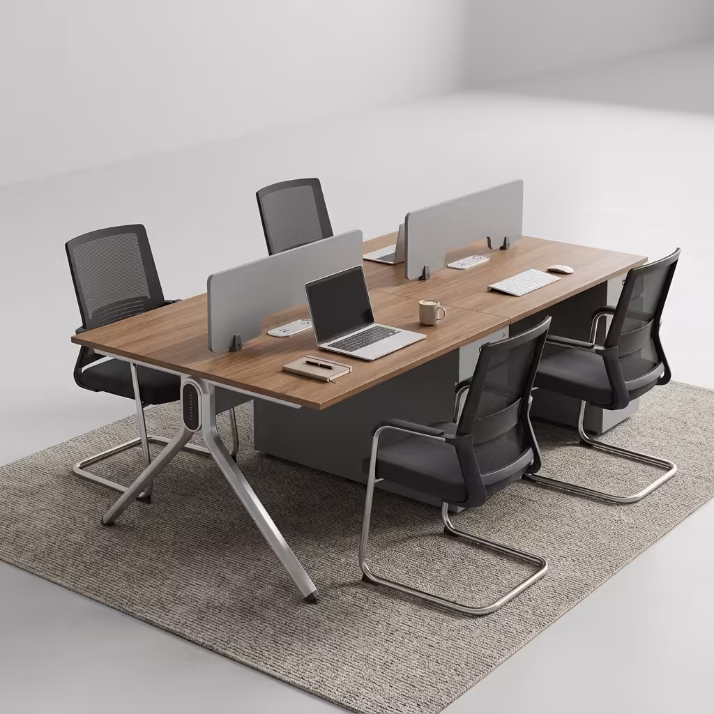 Premium 4-Way Modern Staff Office Workstation featuring a 4-person back-to-back island layout with walnut woodgrain desktops, integrated matte grey privacy partition screens, a heavy-duty angled aluminum A-frame base, and a central box wire enclosure, paired with four black mesh visitor chairs with chrome cantilever sled bases, resting on a textured beige area rug inside a modern minimalist office.