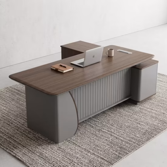 Premium 1.8M Executive Director's Office Desk in a dark charcoal-brown woodgrain finish, featuring a vertical matte grey fluted slatted front modesty panel, an integrated left-side return storage console, a right-side drawer block pedestal, a desktop supporting an open silver laptop, a leather notebook, and a ceramic mug, resting on a textured striped grey area rug.