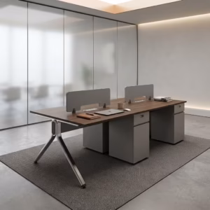 Premium 4-Way Modern Staff Office Workstation featuring a 4-person back-to-back island layout with walnut woodgrain desktops, integrated matte grey privacy partition screens, a heavy-duty angled aluminum A-frame base, and a central box wire enclosure, paired with four black mesh visitor chairs with chrome cantilever sled bases, resting on a textured beige area rug inside a modern minimalist office.