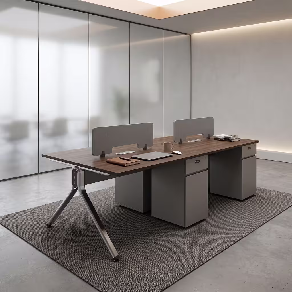 Premium 4-Way Modern Staff Office Workstation featuring a 4-person back-to-back island layout with walnut woodgrain desktops, integrated matte grey privacy partition screens, a heavy-duty angled aluminum A-frame base, and a central box wire enclosure, paired with four black mesh visitor chairs with chrome cantilever sled bases, resting on a textured beige area rug inside a modern minimalist office.