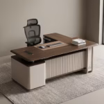 Premium 2.2M Executive CEO's Office Desk featuring a rich walnut woodgrain finish, an integrated tan leather desk blotter mat supporting a wireless mouse and keyboard, a front modesty panel with an off-white vertical fluted slatted design, and an attached side return storage console supporting stacked books, paired with a high-back black mesh office chair on a textured grey area rug.