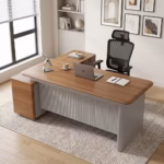Premium 1600MM Executive L-Shaped Office Desk featuring a rich walnut woodgrain finish, a matte grey vertical fluted slatted front modesty panel, and an attached side return storage console supporting a tablet stand, laptop, coffee mug, and notebooks, paired with a high-back black mesh office chair on a textured cream area rug.