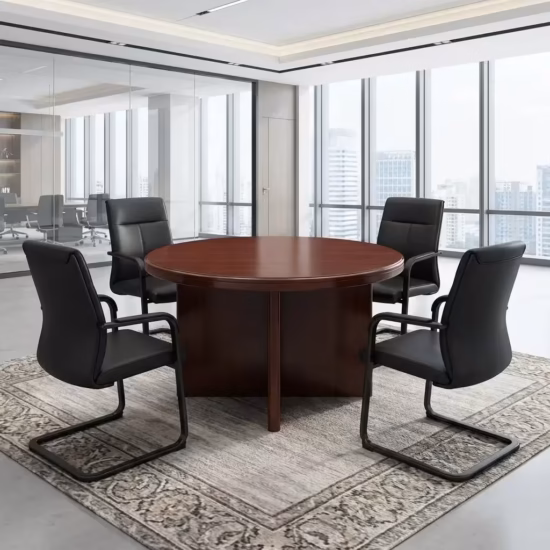 Premium 4-Seater Wooden Meeting Table featuring a thick round top panel in a rich cherry-mahogany woodgrain finish, supported by a heavy-duty centered cross-panel wooden pillar base, surrounded by four black mesh visitor chairs with chrome cantilever sled bases, resting on a smooth grey concrete studio floor next to a massive city-view window.
