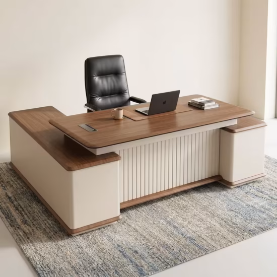 Premium 2.4M Modern L-Shaped Executive Desk in a rich walnut woodgrain and off-white dual-tone finish, featuring a front modesty panel with vertical off-white fluted slats, an integrated left-side return storage cabinet console with a lock, and two white supporting side pedestals, supporting an all-in-one desktop computer, a wireless keyboard and mouse, a notebook with a pen, a ceramic mug, and a metallic pen holder, resting on a textured gray patterned area rug.