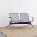 Premium 2-Link Steel Office Waiting Bench featuring two linked silver metallic chairs with perforated mesh patterns, integrated curved polished chrome side armrests, and sturdy silver metal arching legs with adjustable leveling glides, standing on a textured tan woven rug inside a modern corporate reception room.