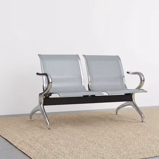 Premium 2-Link Steel Office Waiting Bench featuring two linked silver metallic chairs with perforated mesh patterns, integrated curved polished chrome side armrests, and sturdy silver metal arching legs with adjustable leveling glides, standing on a textured tan woven rug inside a modern corporate reception room.
