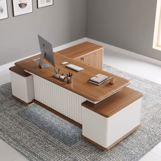 Premium 2.4M Modern L-Shaped Executive Desk in a rich walnut woodgrain and off-white dual-tone finish, featuring a front modesty panel with vertical off-white fluted slats, an integrated left-side return storage cabinet console with a lock, and two white supporting side pedestals, supporting an all-in-one desktop computer, a wireless keyboard and mouse, a notebook with a pen, a ceramic mug, and a metallic pen holder, resting on a textured gray patterned area rug.