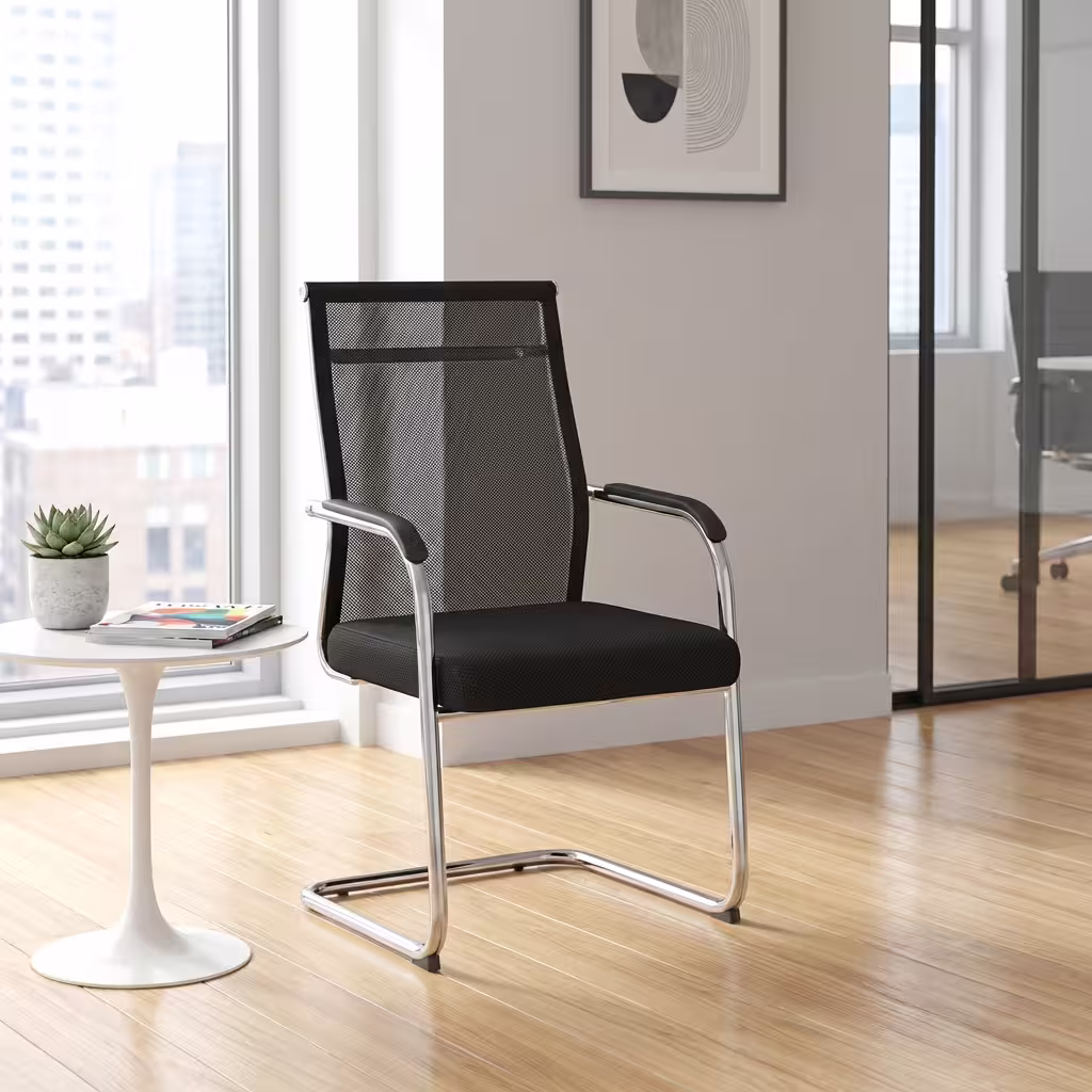 Premium Cantilever Mesh Office Visitor Seat featuring an open-airflow black mesh backrest, integrated chrome armrests with black top pads, a plush black fabric seat cushion, and a highly reflective continuous chrome steel cantilever sled base, standing on a polished hardwood floor next to a white round pedestal side table.