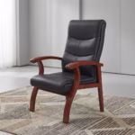 Premium Executive Bliss Visitor Office Chair featuring a high-backrest upholstered in segmented black leather, sweeping integrated solid wood armrests and structural legs finished in a rich mahogany stain, standing on a large textured geometric grey and cream area rug over a smooth polished studio floor.