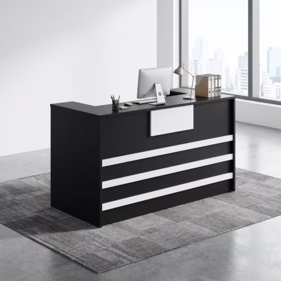 Premium 1400mm Custom Front Reception Office Desk in a bold matte black and white dual-tone finish, showing an integrated upper privacy counter holding an all-in-one computer screen, a silver articulating desk lamp, and binder organizers, detailed with three horizontal white front accent bands and a central white logo mount board, resting on a textured gray geometric carpet tile rug inside a sunlit skyscraper office room.