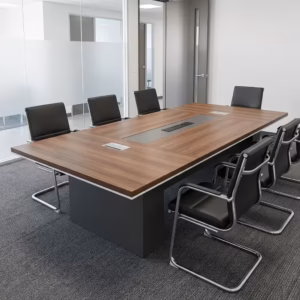 Premium 2M Executive Office Boardroom Table in a rich walnut woodgrain finish, showcasing a massive rectangular top panel with a center-running dark gray accent band and silver flip-top power grommets, anchored by two heavy-duty matte charcoal gray block leg pillars, surrounded by black leather cantilever boardroom chairs on textured gray office carpeting.