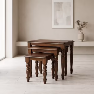 Premium Classic Wooden Nesting Stool Set in a rich dark walnut woodgrain finish, showcasing three stacked rectangular accent tables with ornate hand-carved column legs graduated by size, standing flat on smooth light grey flooring inside a bright contemporary minimalist room.