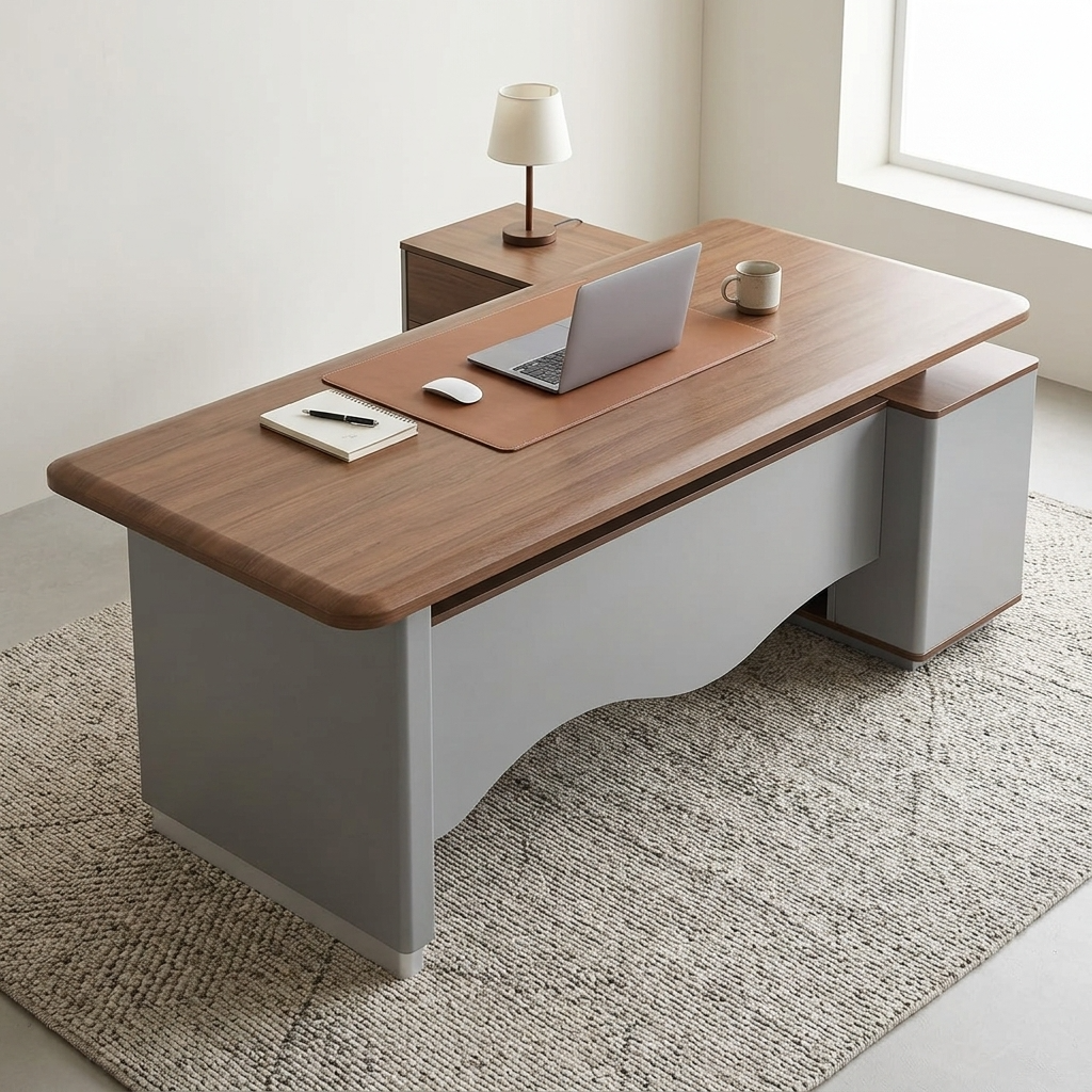 Premium 2.0M Executive L-Shaped Office Desk featuring a rich walnut woodgrain finish, an integrated tan leather desk blotter mat supporting an open laptop computer and a wireless mouse, a front modesty panel with a wave-curved matte grey design, and an attached side return storage console supporting a minimalist table lamp, resting on a textured cream and brown area rug.