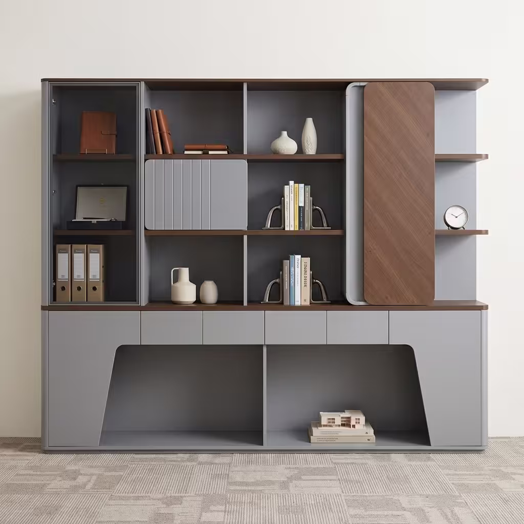 Premium Luxury Office Wooden Storage Cabinet in a dual-tone matte grey and walnut woodgrain finish, showcasing a glass door case on the left with leather journals and folders, open bookshelves with a grey ribbed sliding panel, a vertical rounded wood panel block on the right, and lower push-open drawers above a geometric open base cutout with an architectural model, standing on grey textured office carpet tiles.